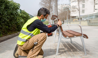 Operari treballant en un pla d'ocupació pintant bancs a l'espai públic